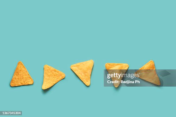 mexican nacho corn chips lying on a blue turquoise background. mexican cuisine. - tortilla chips stockfoto's en -beelden