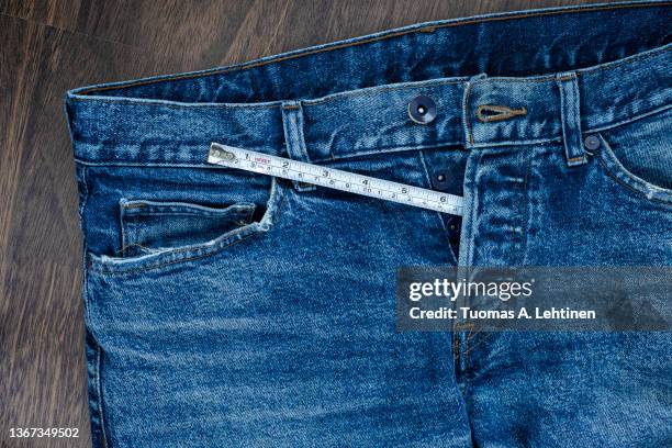 measuring tape coming out from unbuttoned fly of jeans. - größenunterschied stock-fotos und bilder