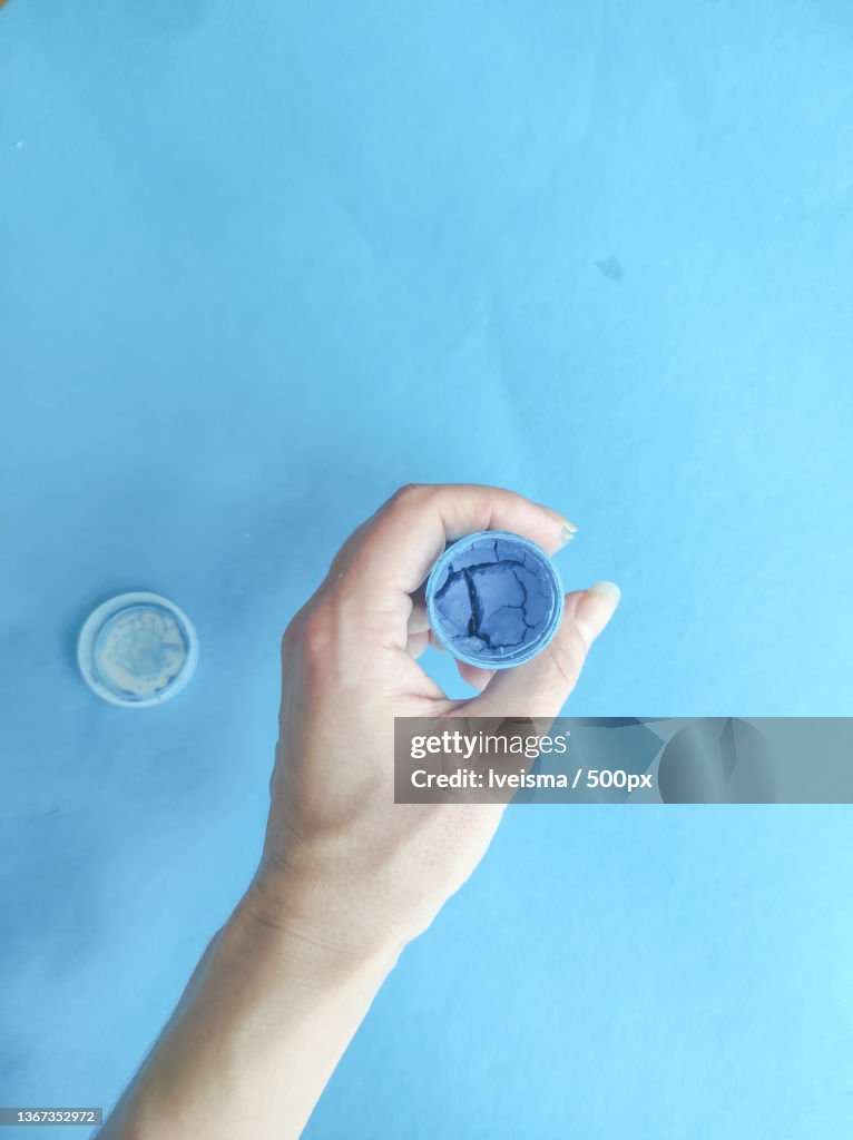 Blue paint,Cropped hand holding condom against blue background