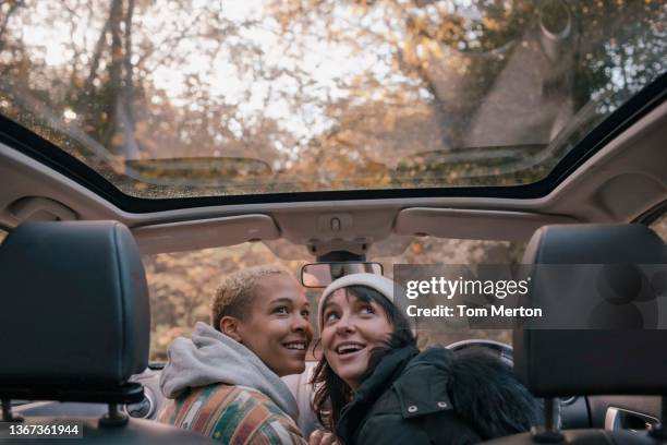 uk, london, richmond, smiling lesbian couple in car - soltak bildbanksfoton och bilder