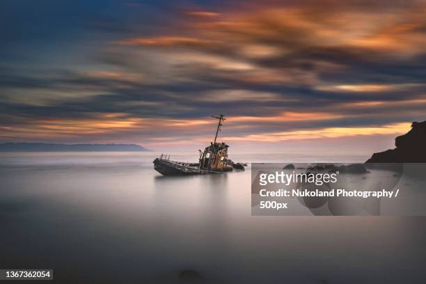 shipwreck,scenic view of sea against sky during sunset - shipwreck stock-fotos und bilder