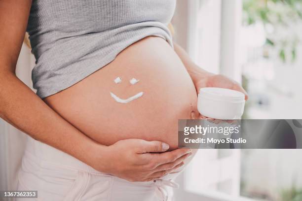 shot of a woman applying cream to her pregnant belly - stretch mark stock pictures, royalty-free photos & images
