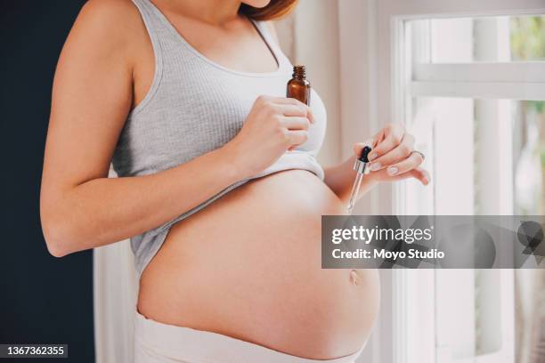 shot of a woman applying oil to her pregnant belly with a dropper - stretch mark stock pictures, royalty-free photos & images