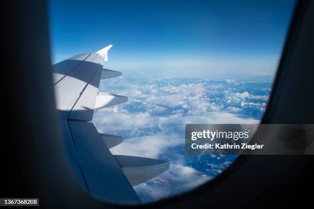 snowcapped mountains seen through airplane window - air travel fotografías e imágenes de stock