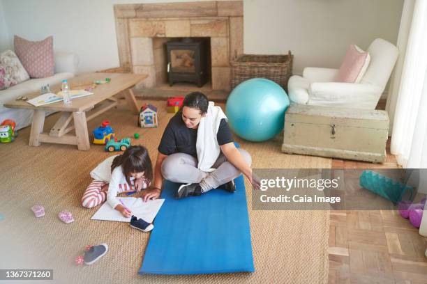 mother on yoga mat watching daughter coloring on living room floor - child yoga elevated view stock pictures, royalty-free photos & images