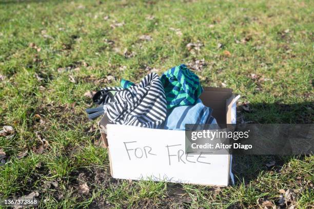 box of clothes on the grass in a park to donate. - holding aloft stock-fotos und bilder