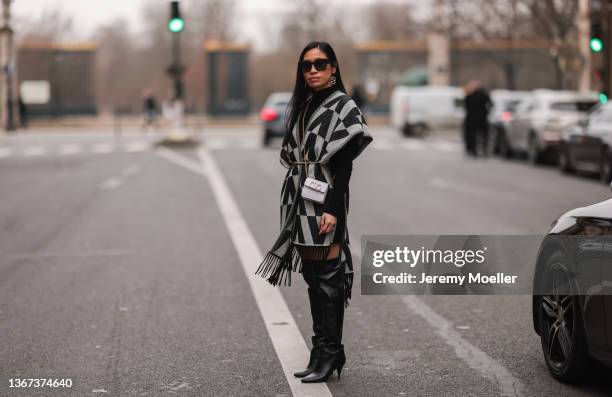 Miki Cheung wears black sunglasses, silver and rhinestoned pendant earrings from Valentino, a black high neck wool pullover, a black and gray V...