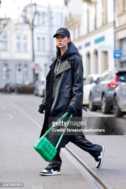 Influencer Nadine Tosun wearing a black college jacket by Celine, a black hoodie by Nadine Tosun the Label, black pants by Nanushka, a black cap by...