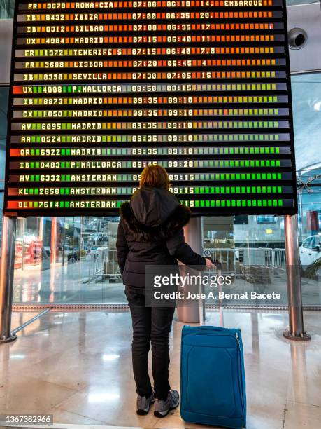 adult woman traveler looking at flight information. - stornierung stock-fotos und bilder