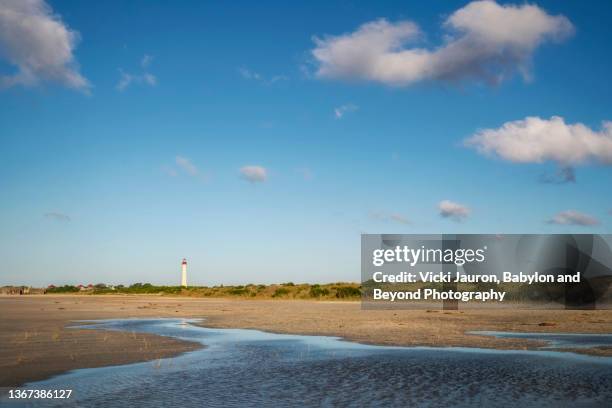 beautiful blue sky with clouds over sand, water and lighthouse at cape may point state park - new jersey landscape stock pictures, royalty-free photos & images