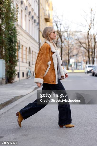 Influencer and model Marlies Pia Pfeifhofer wearing a camel colored jacket by Sandro, a white t-shirt by The Frankie Shop, blue denim jeans pants by...