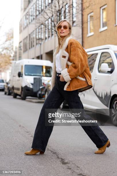 Influencer and model Marlies Pia Pfeifhofer wearing a camel colored jacket by Sandro, a white t-shirt by The Frankie Shop, blue denim jeans pants by...