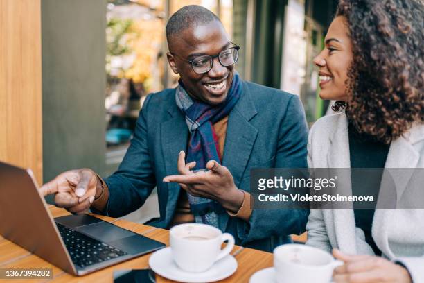 junges paar, das in einem straßencafé sitzt und einen laptop benutzt. - two executive man coffee shop stock-fotos und bilder