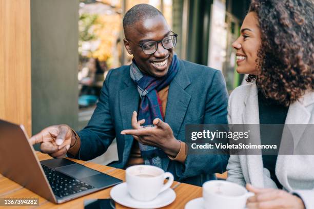 young couple sitting in a sidewalk cafe and using laptop. - coffee meeting stock pictures, royalty-free photos & images