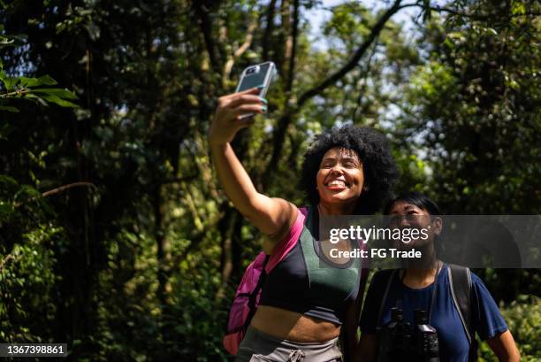 friends taking selfies on the mobile phone in the forest - eco tourism stock pictures, royalty-free photos & images