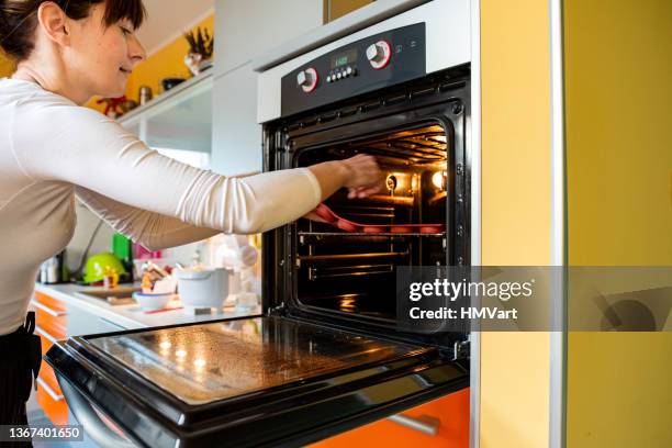 woman puts silicone donuts molds into the oven to bake - silikone stock pictures, royalty-free photos & images