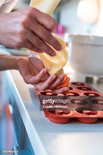 woman pouring the dough into small silicone donuts molds - silikone stock pictures, royalty-free photos & images