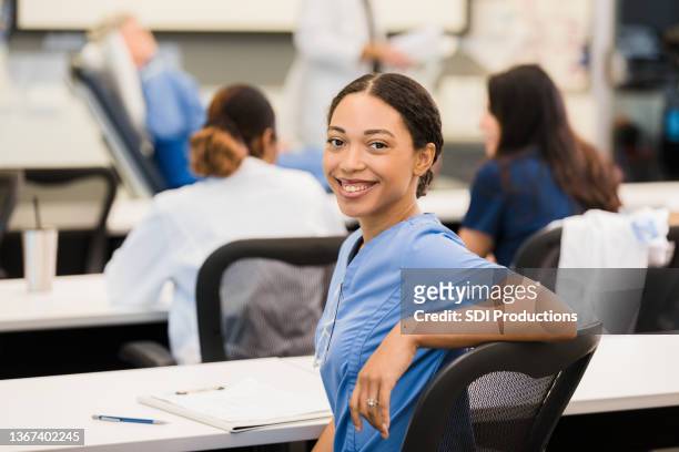 während der vorlesung zur patientenversorgung dreht sich der student um, um für die kamera zu lächeln - smile black white stock-fotos und bilder