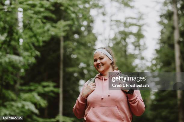 a beautiful female smiling while hiking in the forest - överviktig bildbanksfoton och bilder