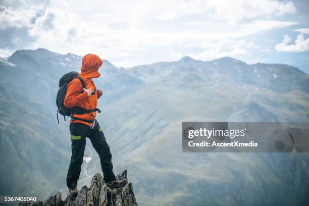 mountaineer scrambles up summit of pinnacle - standing on mountain peak stock pictures, royalty-free photos & images