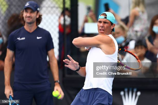 Rafael Nadal of Spain plays a forehand as his coach Carlos Moya looks on during a practice session during day 13 of the 2022 Australian Open at...