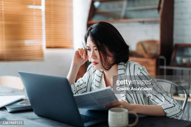 young asian woman handling home finances with laptop, looking worried while going through financial bills. financial plan, tax, spending and budgets, financial problems concept - statement imagens e fotografias de stock