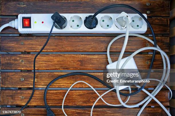 white power strip with cables on a wooden table. - steckerleiste stock-fotos und bilder