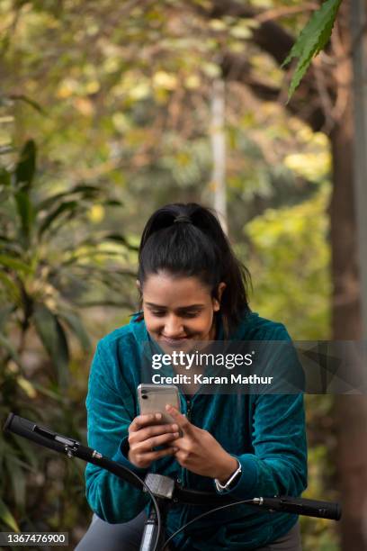 young woman riding bicycle and using mobile phone stock photo - bike headset stockfoto's en -beelden