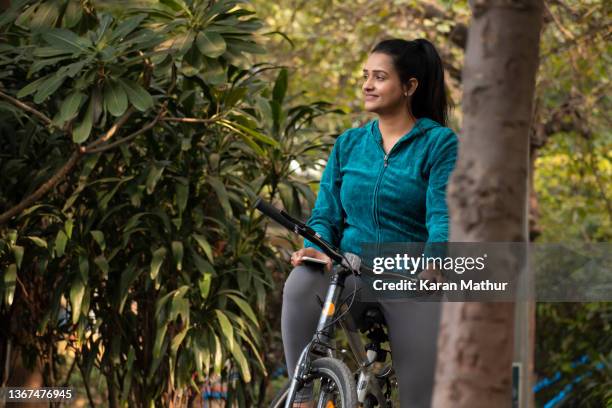 young woman riding bicycle in park stock images - indian riding stock pictures, royalty-free photos & images