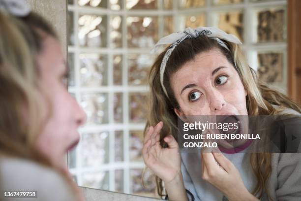young caucasian teenager undergoing facial treatment in front of a mirror. healthcare and medicine concept. - spain teen face imagens e fotografias de stock