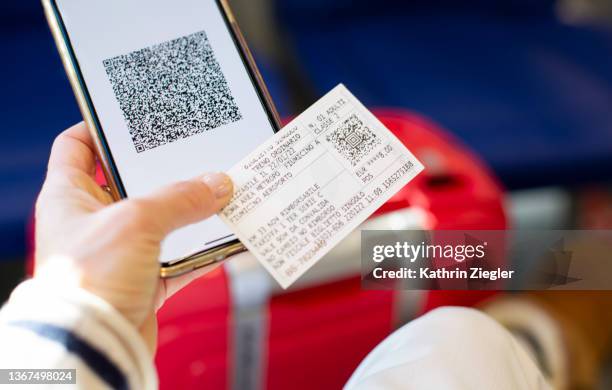 woman holding smart phone with digital green pass and train ticket, close-up of hand - ticket stockfoto's en -beelden
