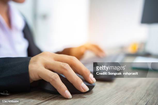 female hand holding a computer mouse with laptop keyboard behind - account manager stock pictures, royalty-free photos & images
