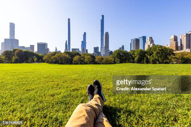 man relaxing in central park looking at manhattan skyline, personal perspective pov, new york, usa - central park stock pictures, royalty-free photos & images