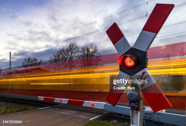 railroad crossing with fast train - vorbeigehen stock-fotos und bilder