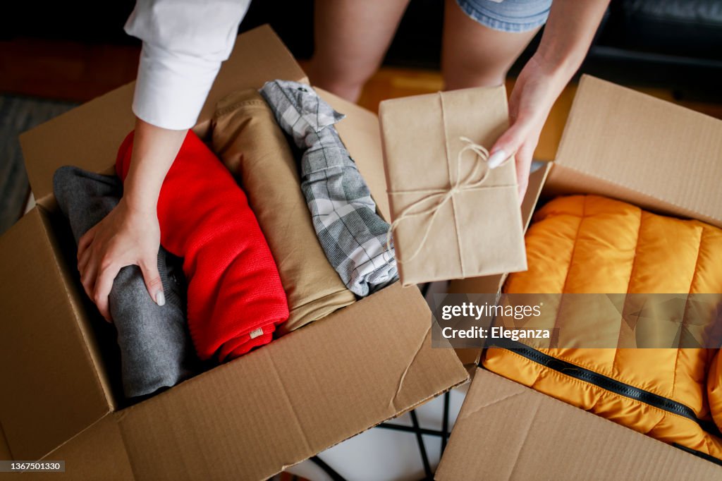 Woman sorting clothing and packing donation box