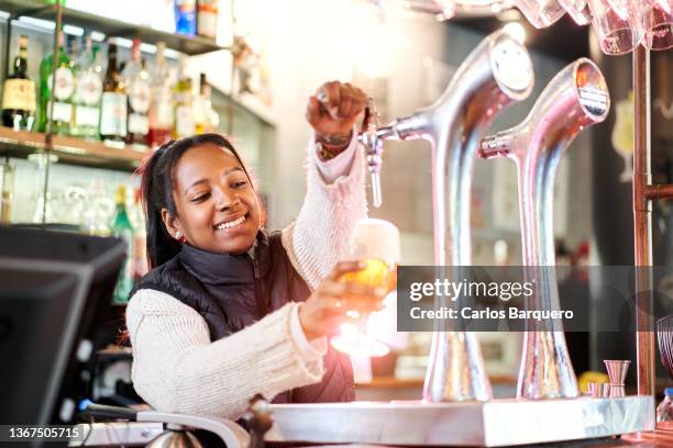 african-american woman at a bar pouring draft beer. - craft beer festival stock pictures, royalty-free photos & images