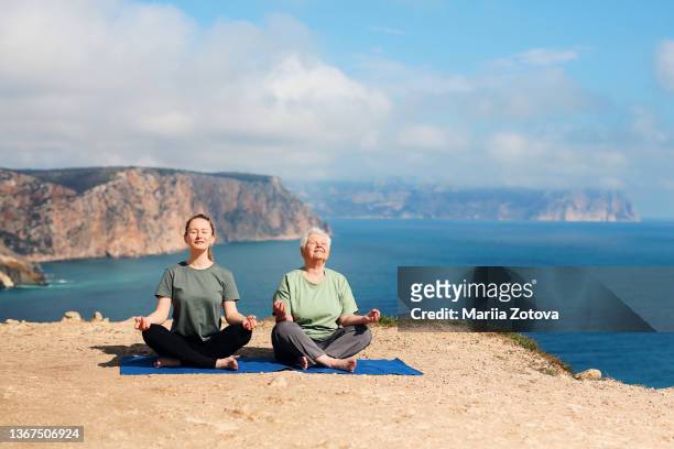 a healthy, positive elderly woman of 80 years is engaged in gymnastics, meditation in nature with an instructor - 30 34 years stock-fotos und bilder