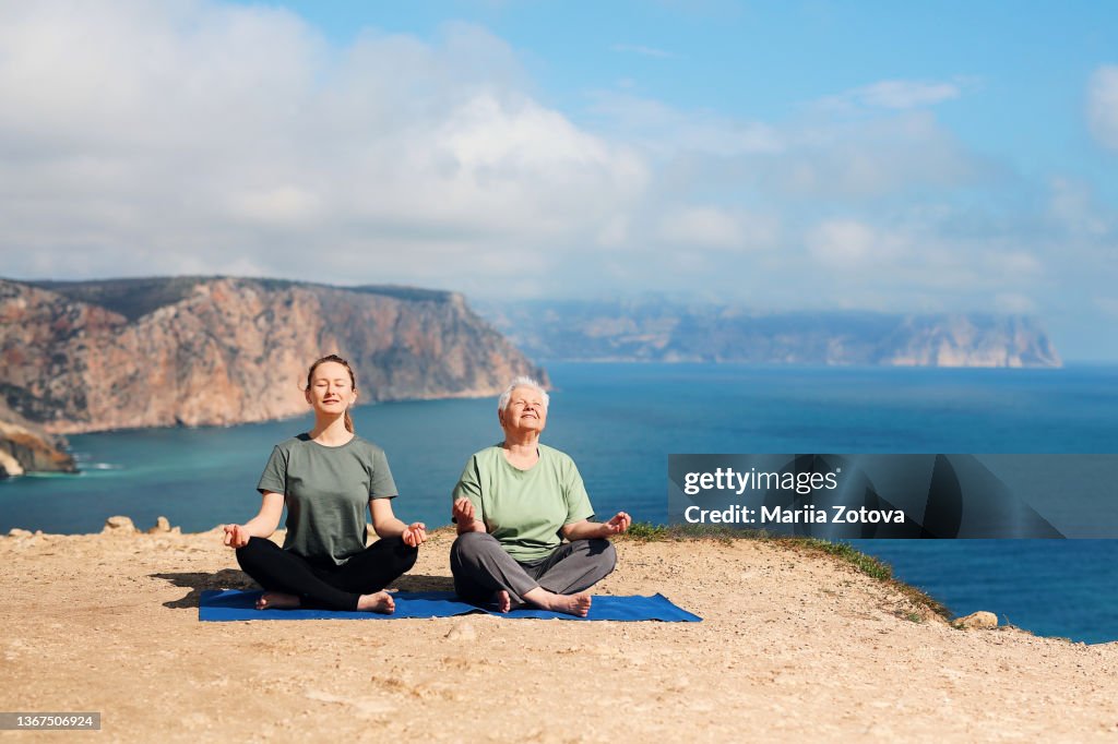 A healthy, positive elderly woman of 80 years is engaged in gymnastics, meditation in nature with an instructor