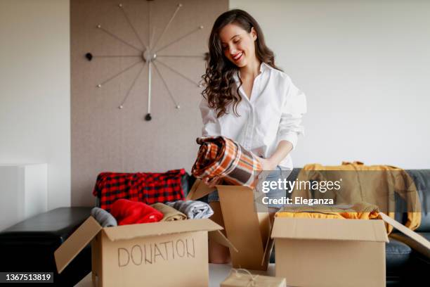 mujer clasificando ropa y empacando caja de donación - guardarropa muebles fotografías e imágenes de stock