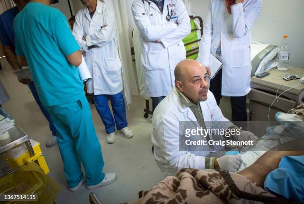 Dr Ali AlAni examines a patient on his ward rounds post surgery accompanied by his surgical team at the MSF Hospital for Reconstructive Surgery on...