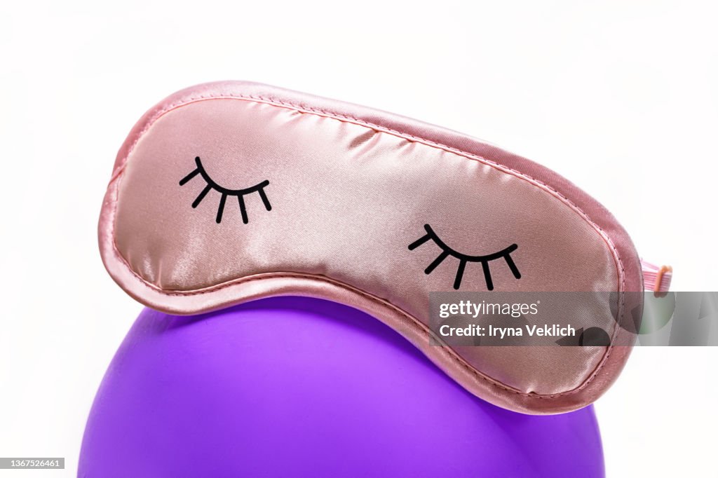 Night  preparation concept with Sleep Eye Mask in delicate pink peach color on an inflatable balloon in Trendy Color of the Year 2022 Very Peri purple violet lavender.