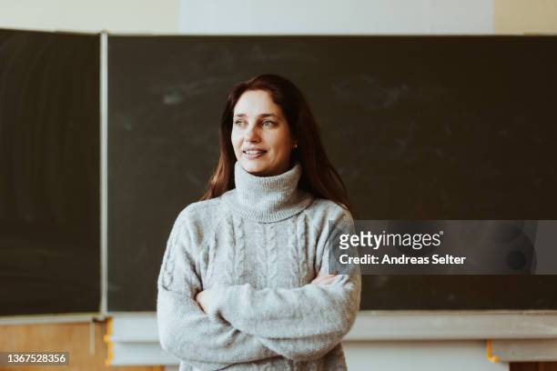 smiling female teacher standing in front a chalkboard - green chalkboard stock pictures, royalty-free photos & images