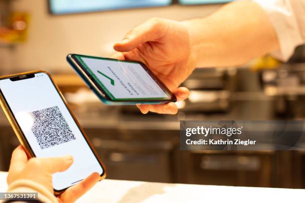 man working at coffee shop scanning customer's digital green pass on mobile phone - bar code stockfoto's en -beelden