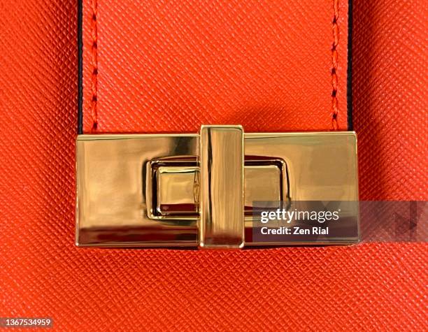 vibrant orange lady's handbag showing flap with metal lock - metallic purse fotografías e imágenes de stock