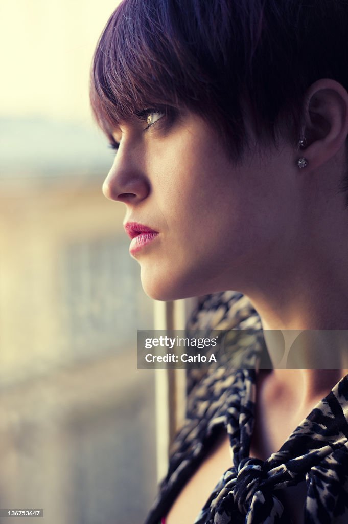 Young woman looking through window