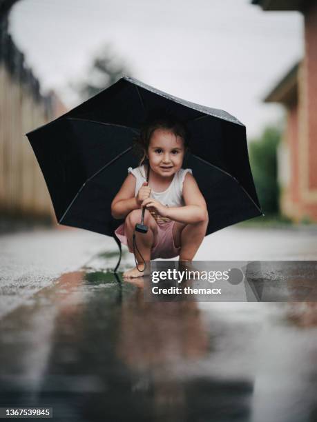 little girl having fun to play with the rain with umbrella - rainy season stock pictures, royalty-free photos & images