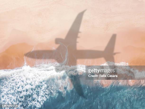 aerial view of an airplane shadow over a sandy beach. - holiday destination stock-fotos und bilder