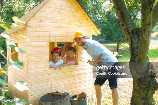 happy family building together children's playhouse. - casa de brinquedo imagens e fotografias de stock