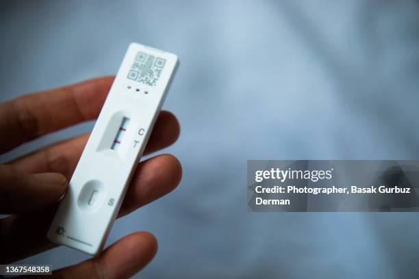 a woman's hand holding a positive test result by using lateral flow rapid test device for covid-19 novel coronavirus. - coronavirus stockfoto's en -beelden