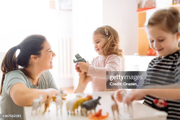 mother and daughters playing with animal toysand enjoying time together - toy animal stock pictures, royalty-free photos & images